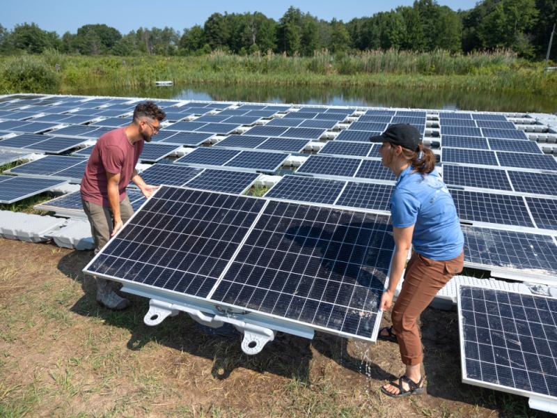 Staff members lift solar panels.