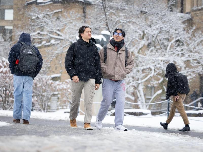 Students pass near McGraw Hall in snow.